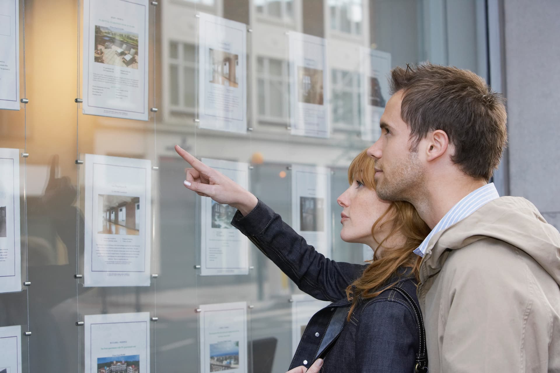 Side view of a young couple looking at window display at real estate office